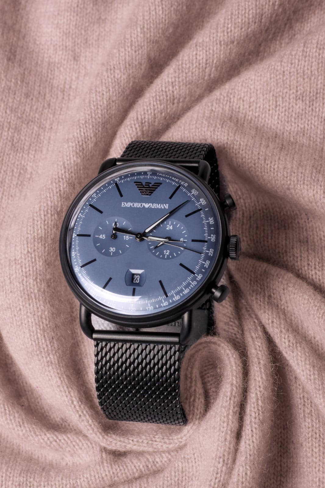 Dark Emporio Armani watch on folded textured pink fabric