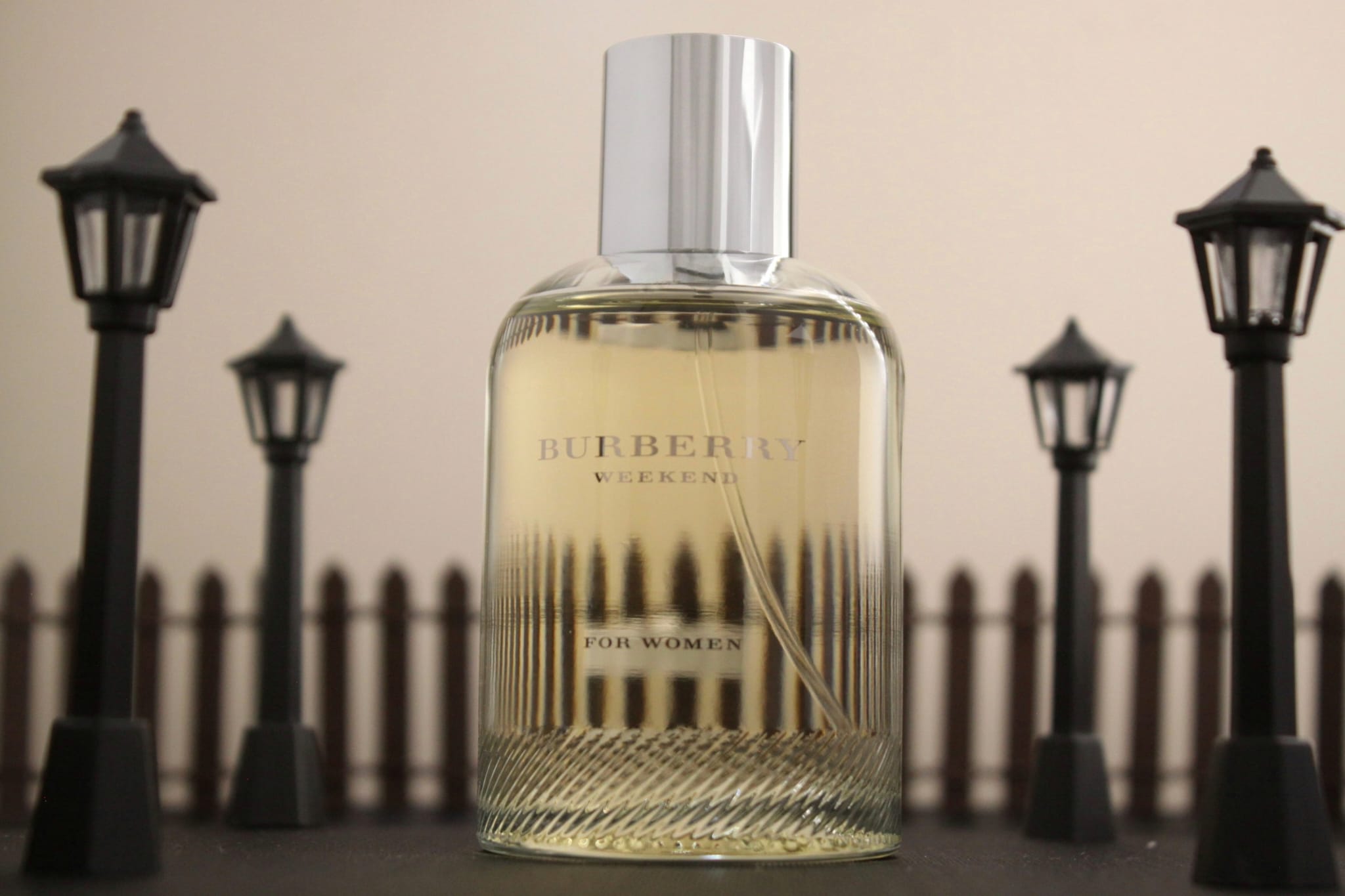 Burberry Weekend bottle staged among miniature lamps and a fence