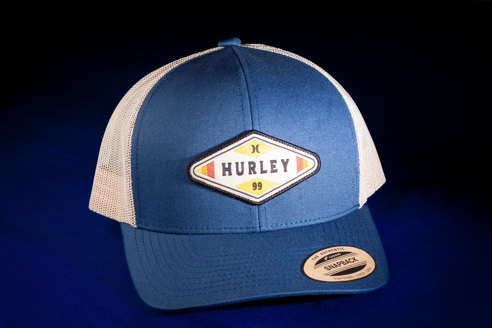 Blue and cream Hurley trucker cap against a dark blue background