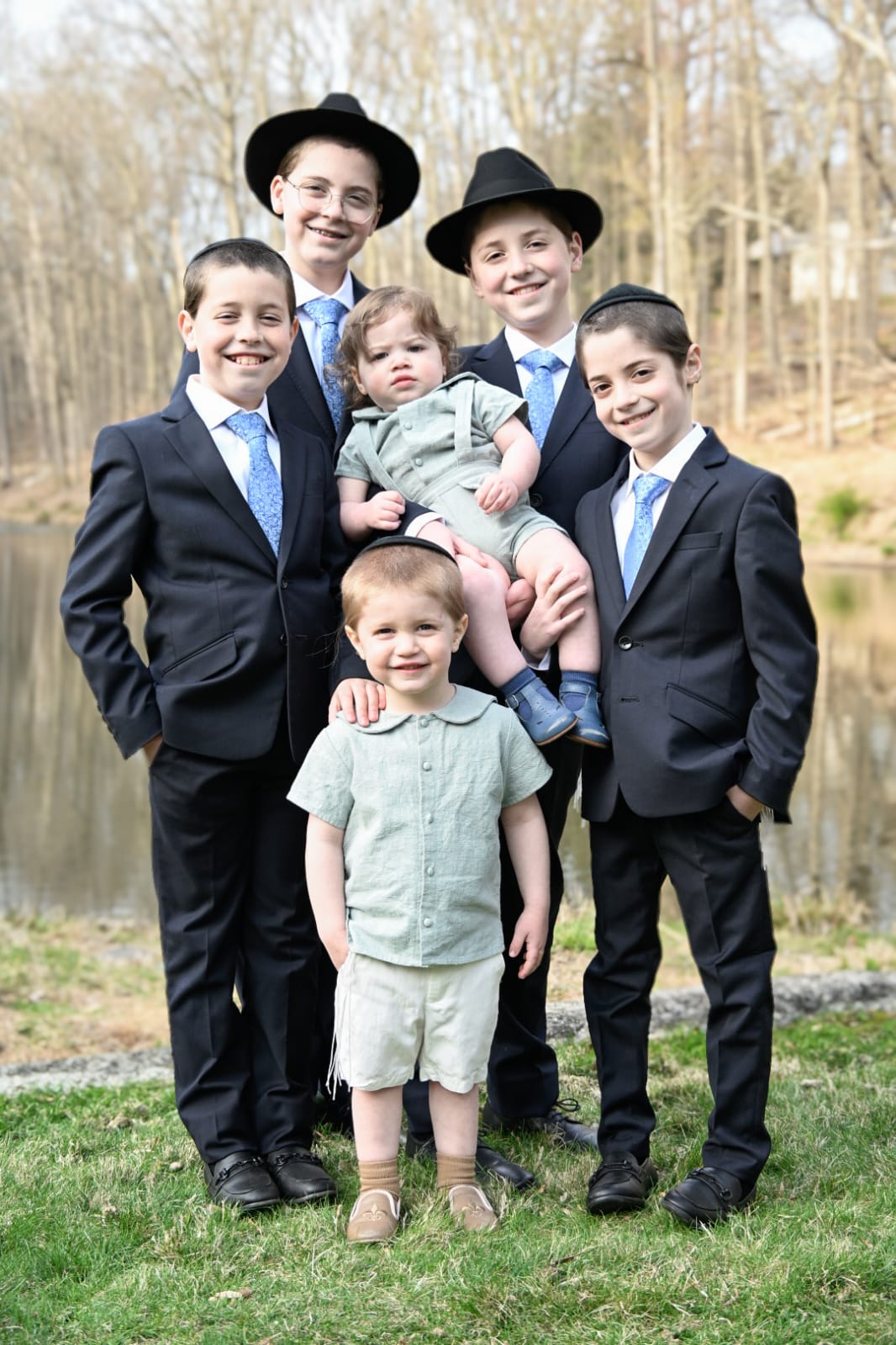 Children in dark suits posed together on grass outdoors