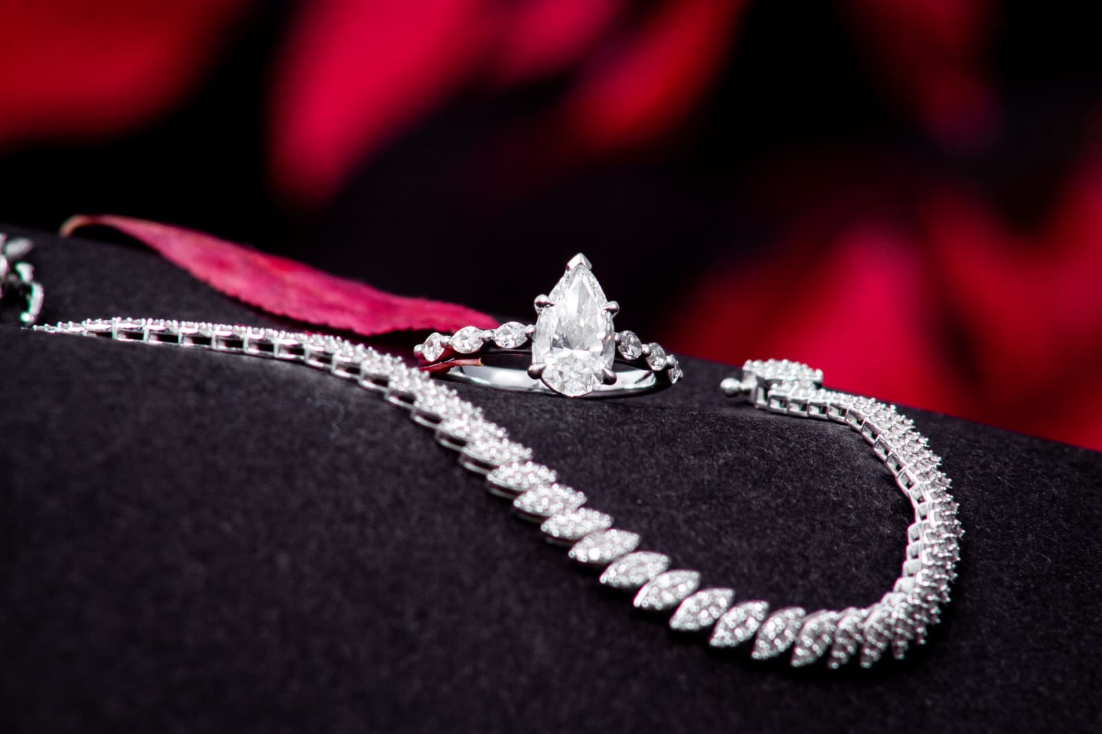 Ring and necklace on dark fabric with a red background