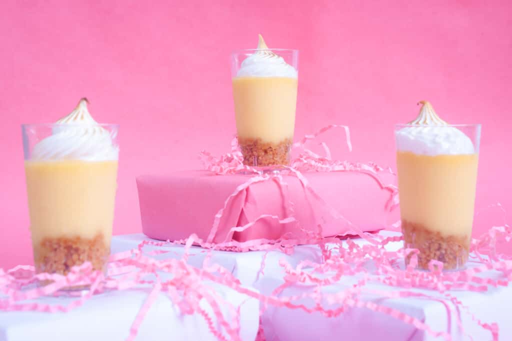 Three layered dessert glasses with meringue styled against pink